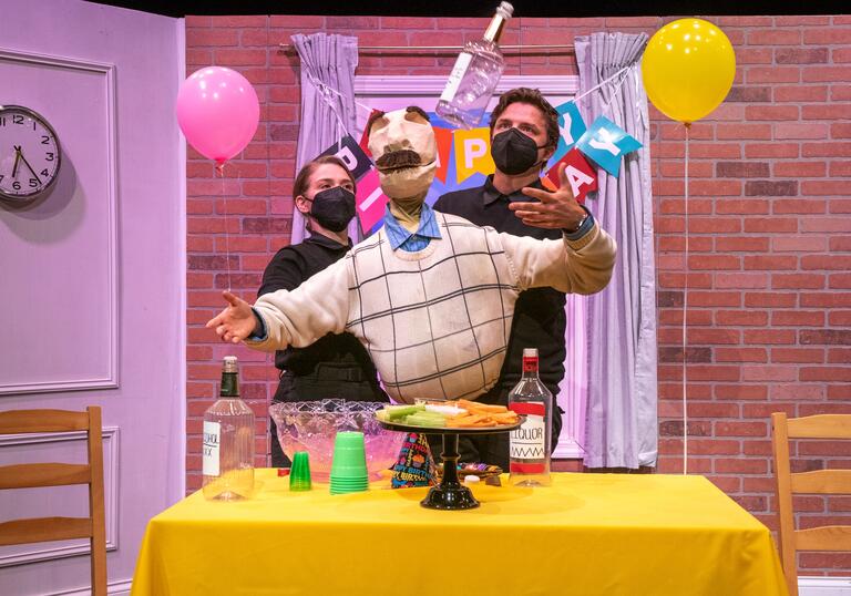 Bill, a large puppet with a moustache, is moved by two puppeteers dressed in black. There are balloons and a happy birthday banner behind them.