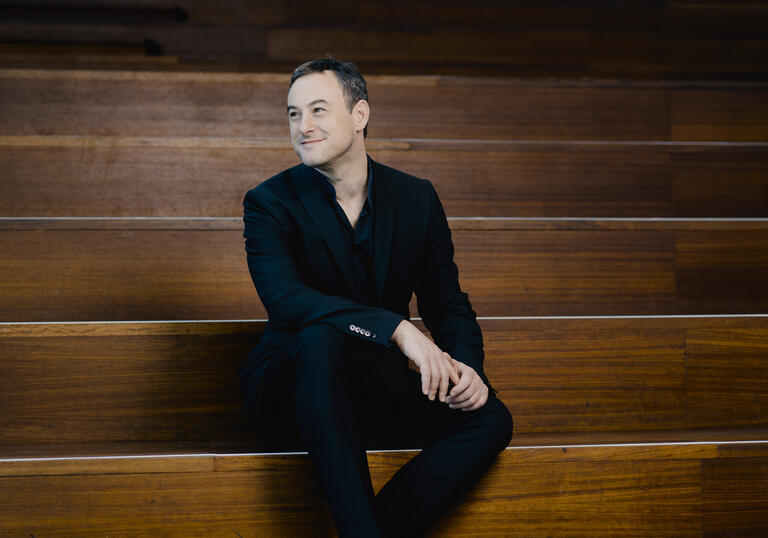 Jonathan Cohen sitting on wooden steps