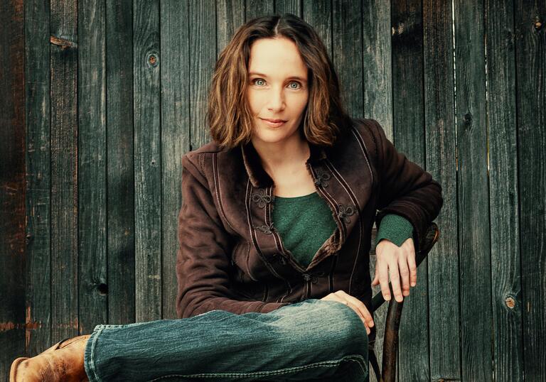 Hélène Grimaud sitting on a chair in front of a wooden fence