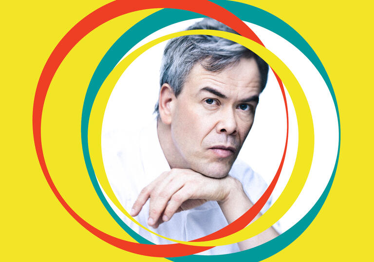 Hannu Lintu leans on his hand. Yellow BBC SO branding surrounds his centralised image 