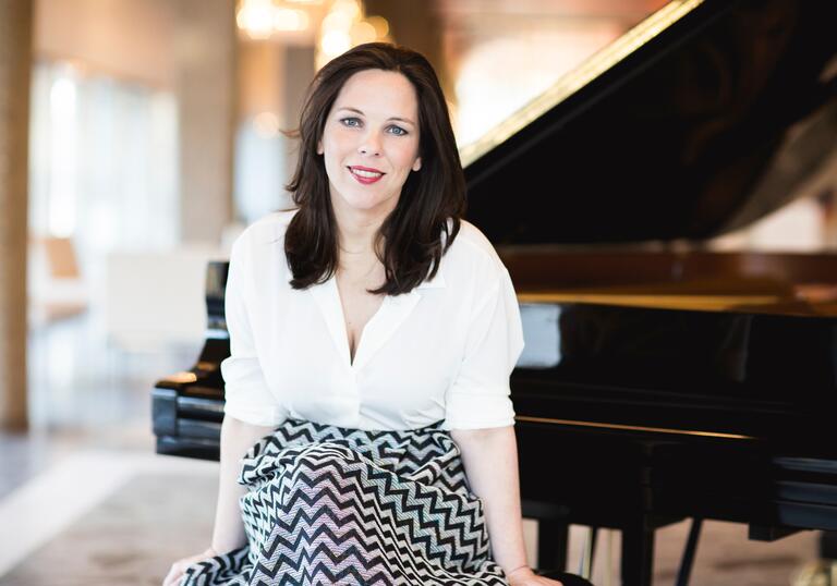 Daria van der Bercken sits on a piano stool, in front of an open grand piano