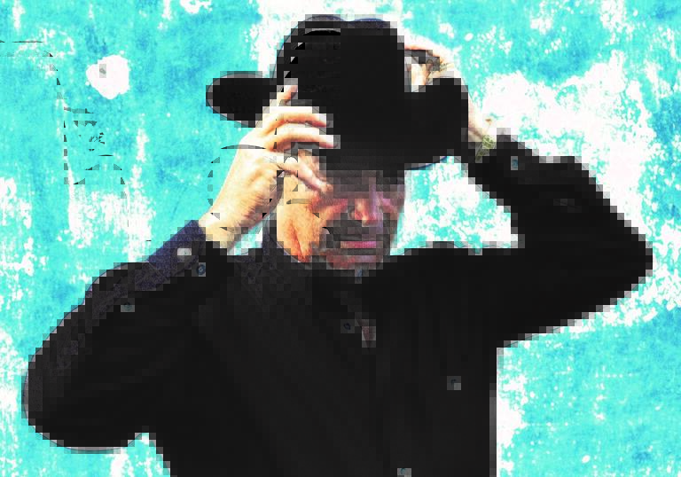 Graphic shot of Eliades wearing a black outfit and cowboy hat