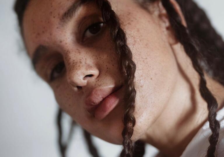 Image of a woman with braids with her head tilted towards the camera