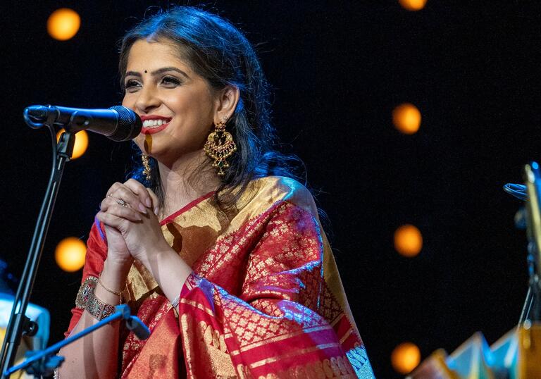 Kaushiki Chakraborty performing on stage smiling in a sari