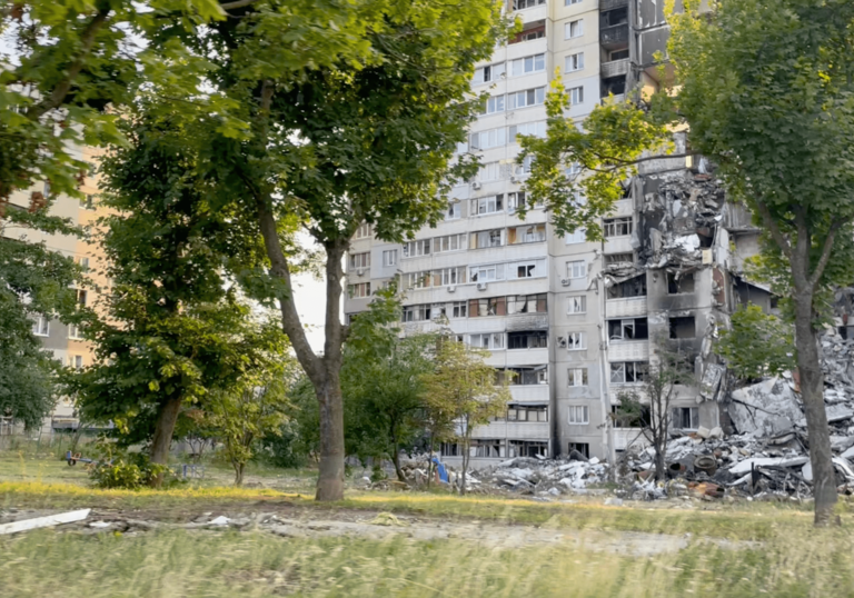 Image of high rise flats with green grass and rubble in foreground