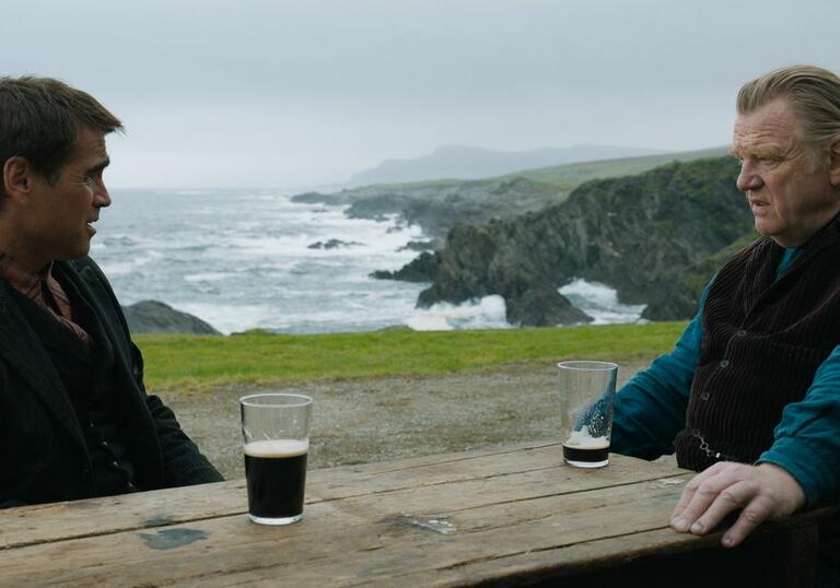Two men speak near a body of water