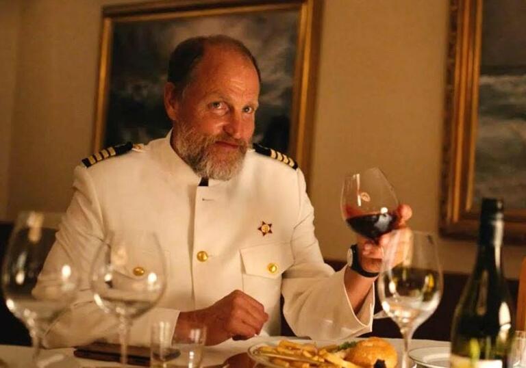 A naval man sits at a table drinking wine