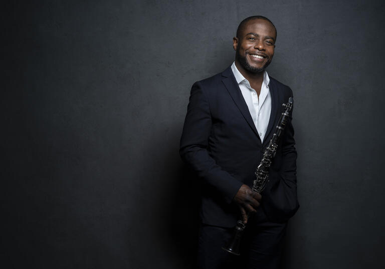 Anthony McGill smiling at the camera while holding his clarinet