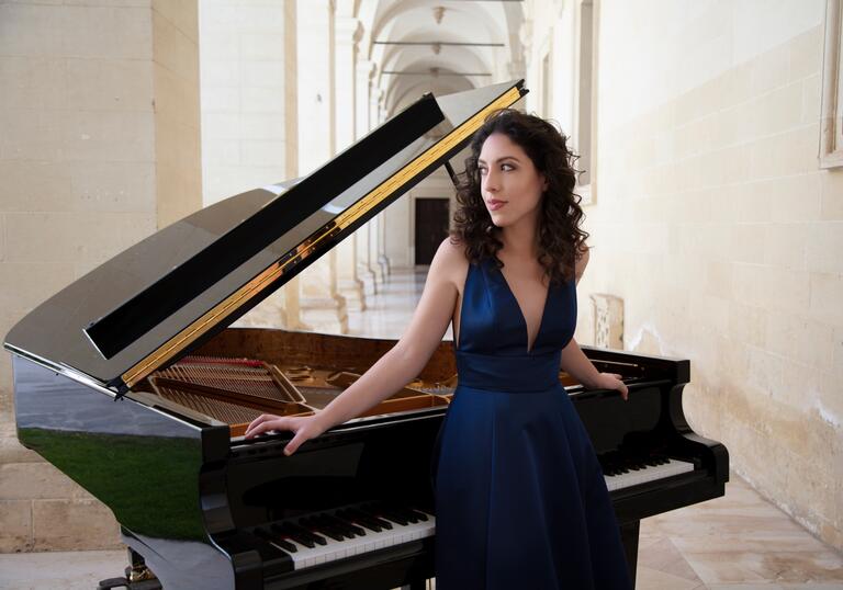 Beatrice Rana standing in front of a grand piano