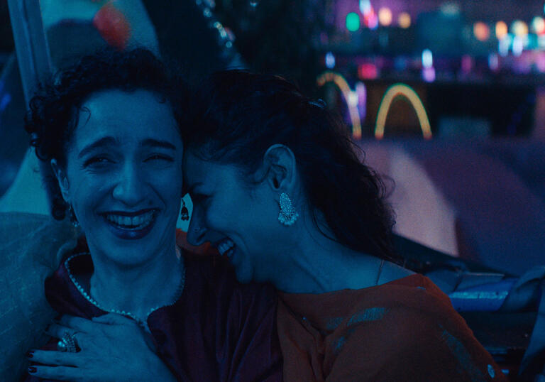 Two woman laugh at night in a still from Joyland