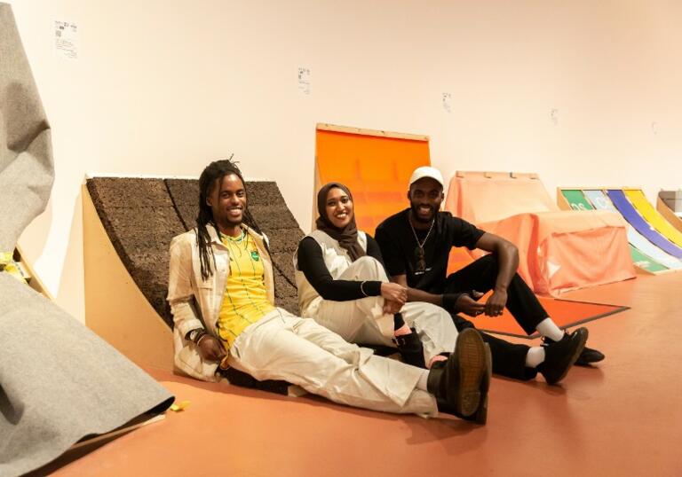 a photo of RESOLVE Collective sitting on their installation in The Curve gallery for them's the breaks