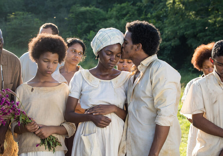 A man kisses a pregnant woman on the head in a still from Parsley. 