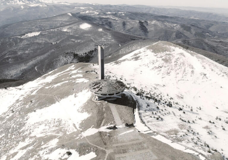 Arial shot of a large industrial building surrounded by snow covered mountains in a still from The Gift.