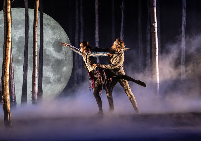A woman and a man dance in a misty forest on stage in Matthew Bourne's Sleeping Beauty