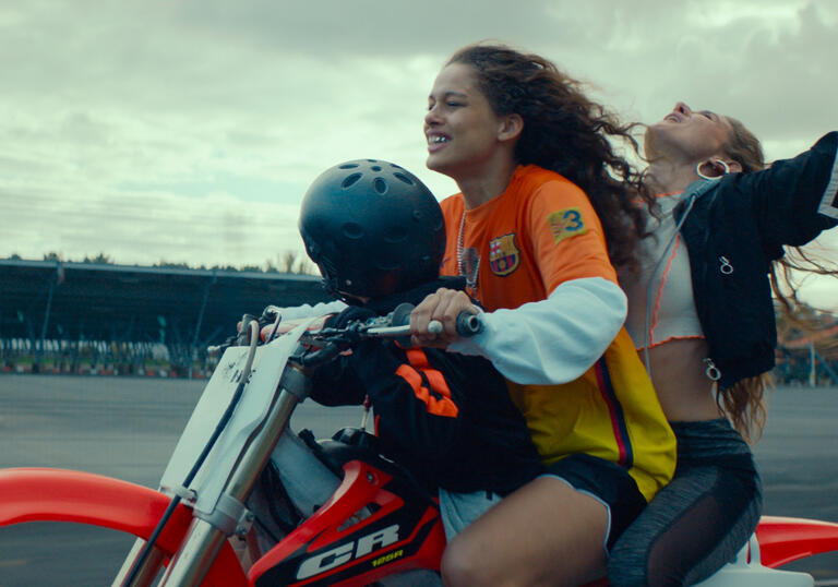 A child and two women drive on a dirt-bike in a still from Rodeo.