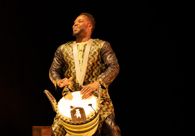 Sidike Dembele plays the drum and smiles on stage