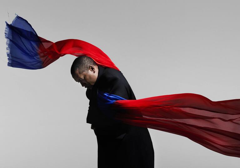 A performer dances while wrapped in a red and blue cloth