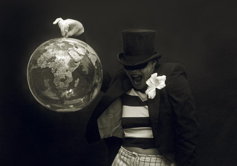 black and white photo of Carie Mae Weems in a top hat, holding up a globe