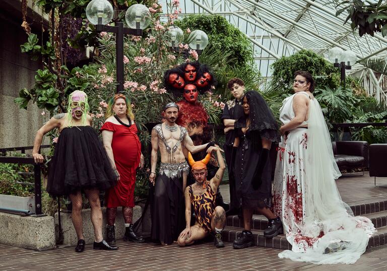 Transpose Burn artists standing in the Barbican Conservatory surrounded by plants. From the left we have Kübra Uzun (they, them),  Kell w Farshéa (they, them), Mustafa Kınalı (aka Mustkika) (any pronouns), Akış Ka (they, them), Dani Dinger (any pronouns),CN Lester (they, them), Ifeoluwa (they, them) and i-Gemini (he, him)