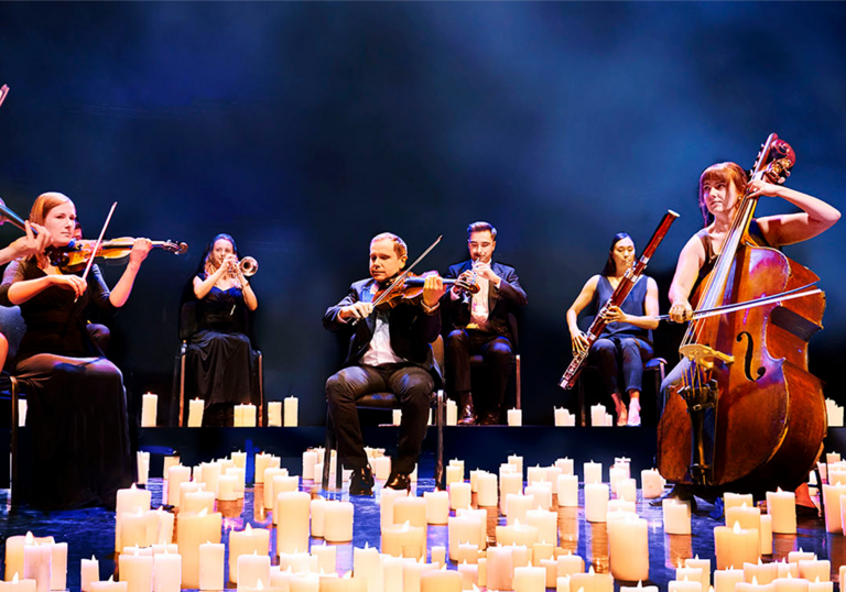 Musicians from the Mozart Festival Orchestra performing while surrounded by candles at their feet