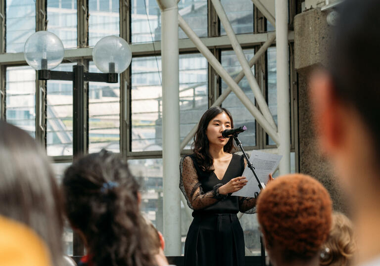 performer wearing a black dress standing in front of a microphone inside the conservatory