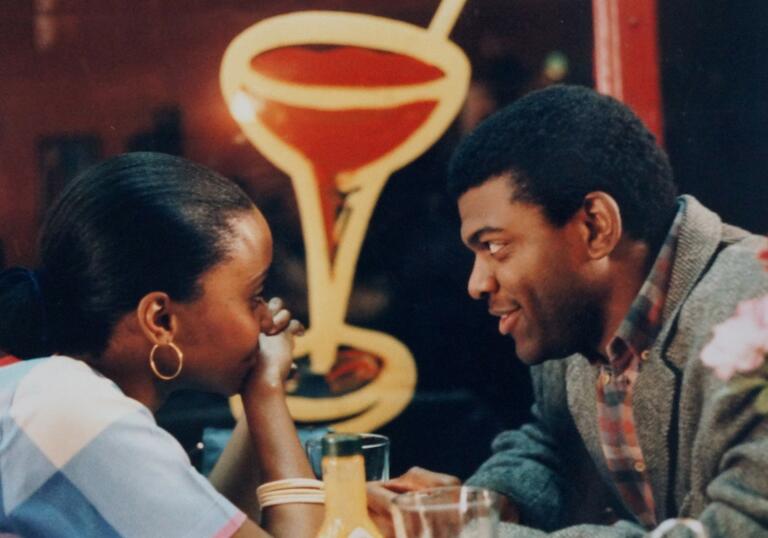 A man and a woman sit close opposite each other in a New York diner