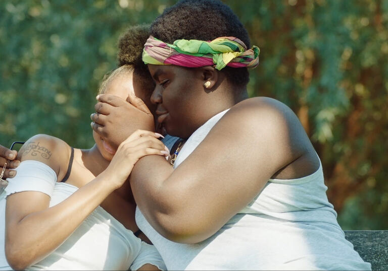 A boy embraces his girlfriend outside