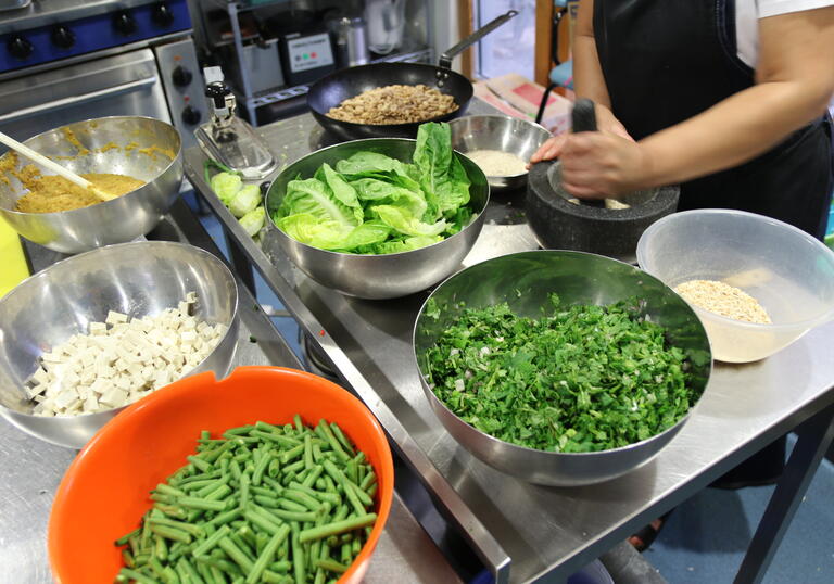 Fresh spices and herbs in bowls, being ground in a kitchen