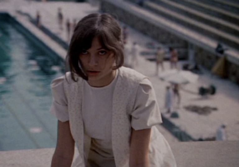 A woman stares to camera with a swimming pool in the background 