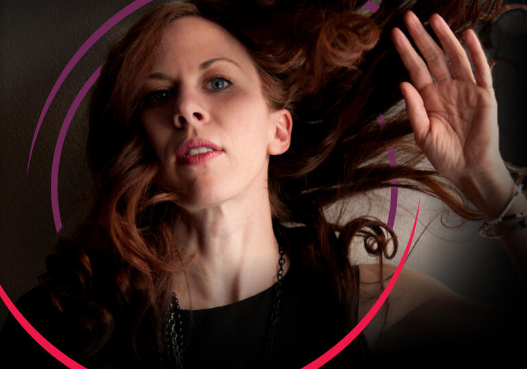 Missy Mazzoli with her hand up by her face and her hair blowing in the wind, with circular purple and pink swirls around her head