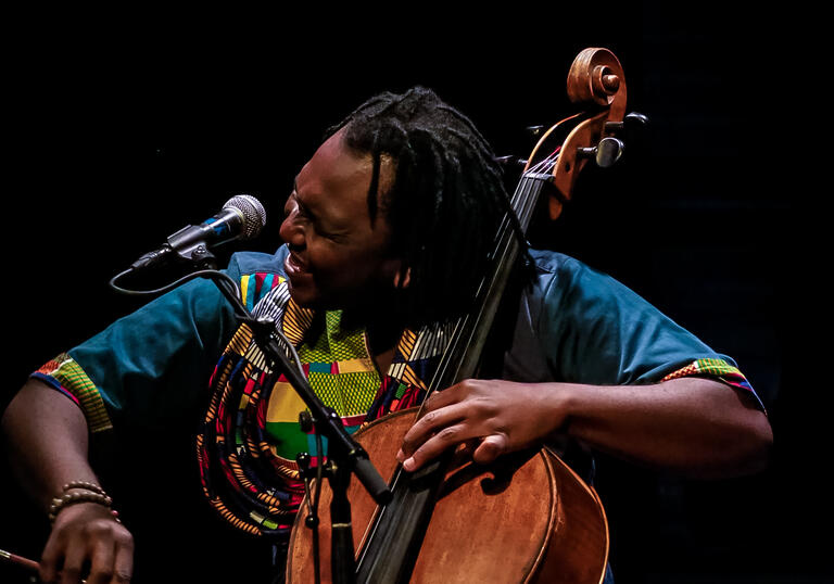 Abel Selaocoe playing his cello against a black background