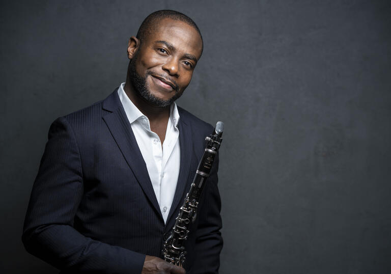 Anthony McGill smiling at the camera while holding his clarinet