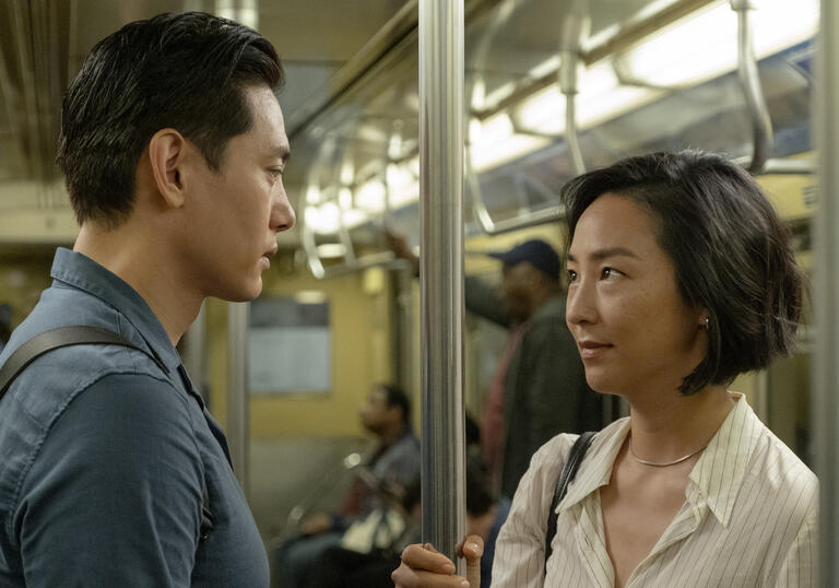 A man and a woman look at each other on the subway