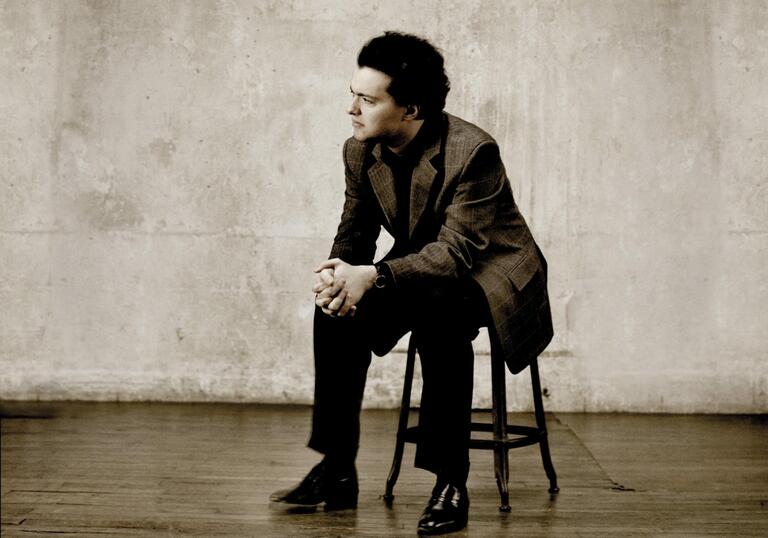 Evgeny Kissin sitting on a stool with his hands clasped