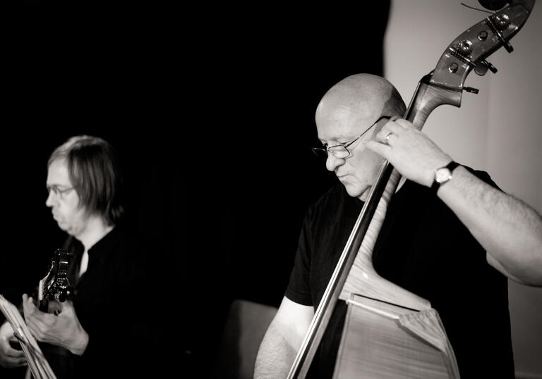 Black and white photo of Gavin Bryars playing the double bass and James Woodrow on the guitar