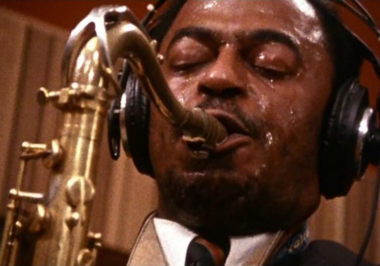 A close up of a man playing a saxophone.