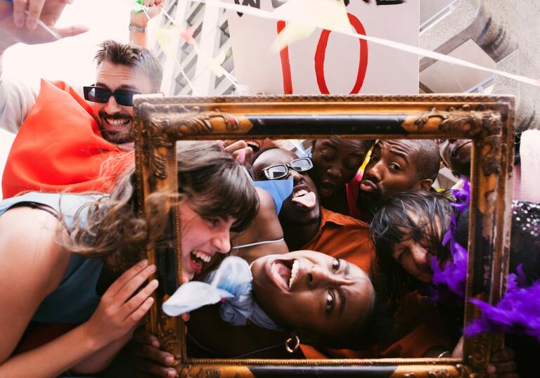 The PappyShow company pile on top of each other, smiling and laughing, surrounded by inflatable frames, boards and colourful clothing.