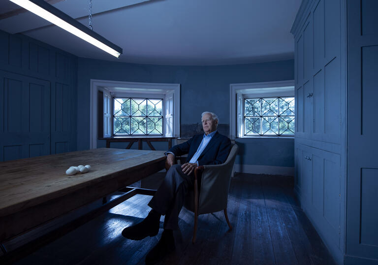 A man in a suit sits in a chair.