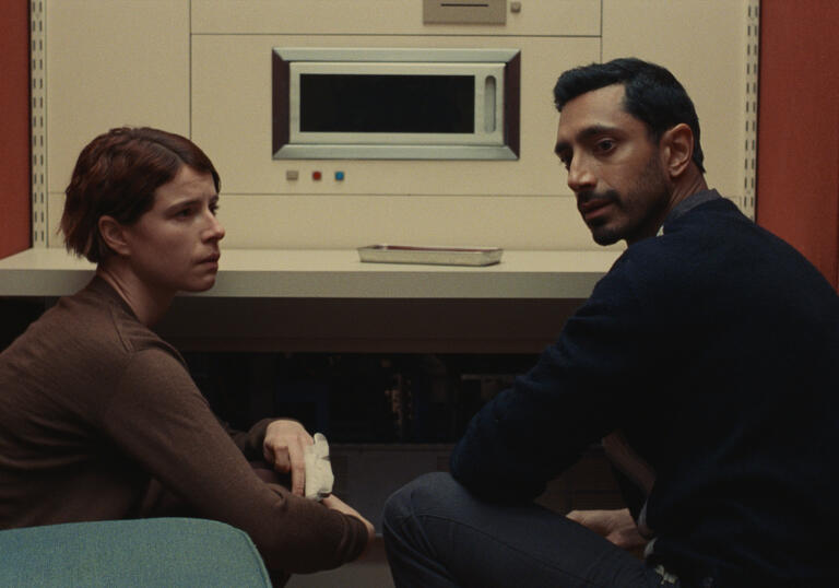 A man and a woman sit in front of a vintage looking computer.