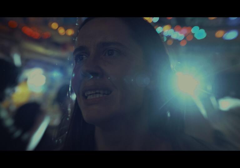 A woman in a brightly lit club looks stressed.