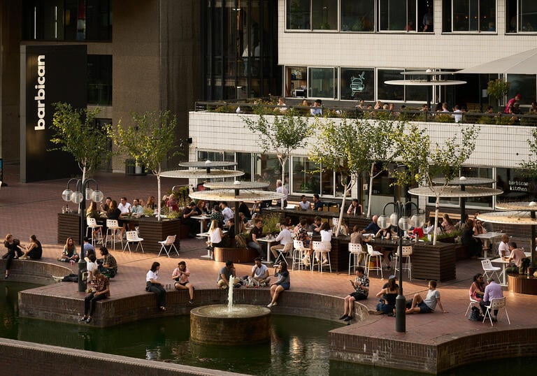 A photo of Lakeside terrace in sunshine, with people sitting together, talking and eating