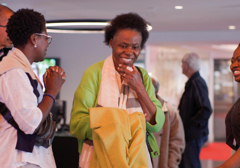 A group of people chat happily in a cinema foyer. 