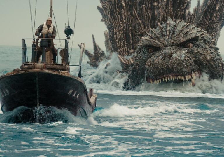 Godzilla chases a small boat through the ocean.