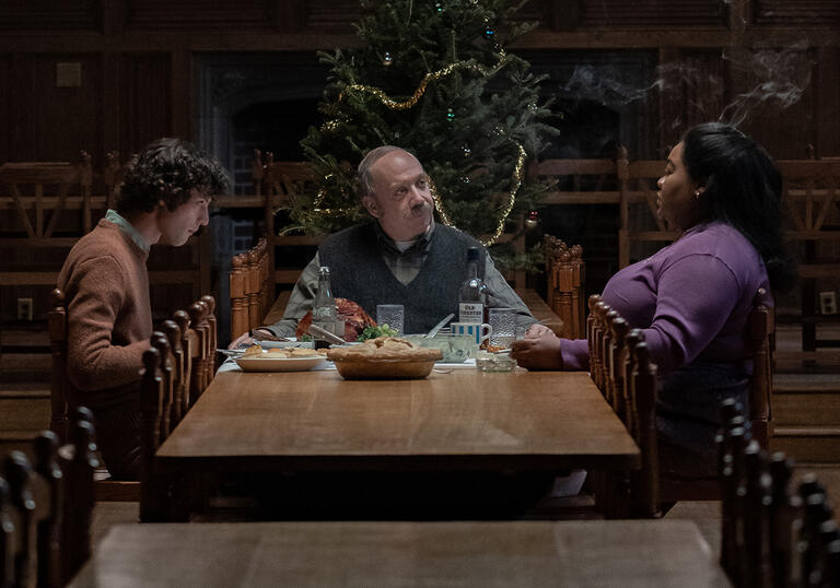 The people sit round a kitchen table having a Christmas dinner.