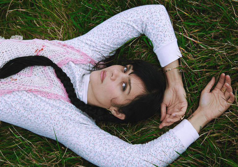 Natasha Khan lies on grass with her arms above her head