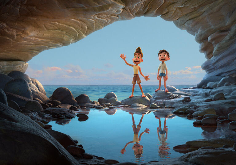 Two young boys stand in a cave by the ocean.
