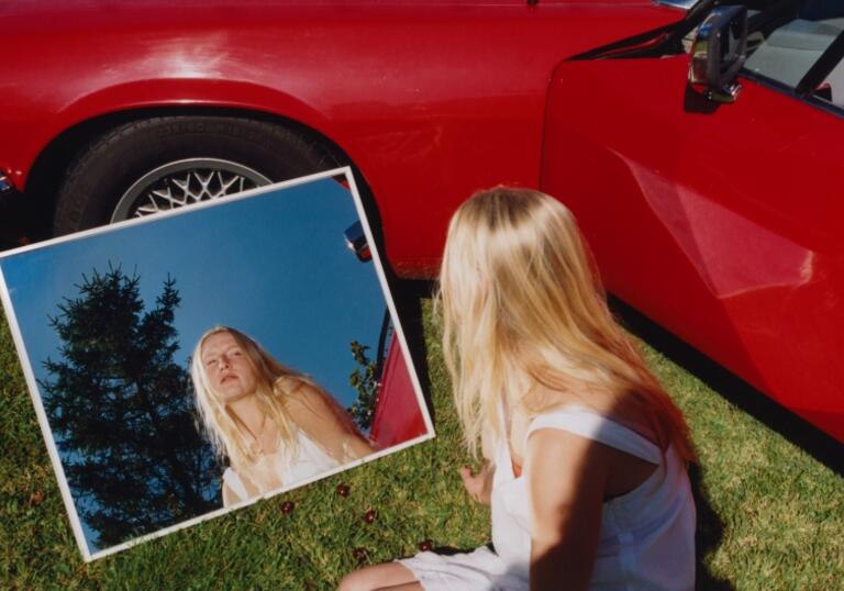 Billie Marten sits on the floor looking in a mirror