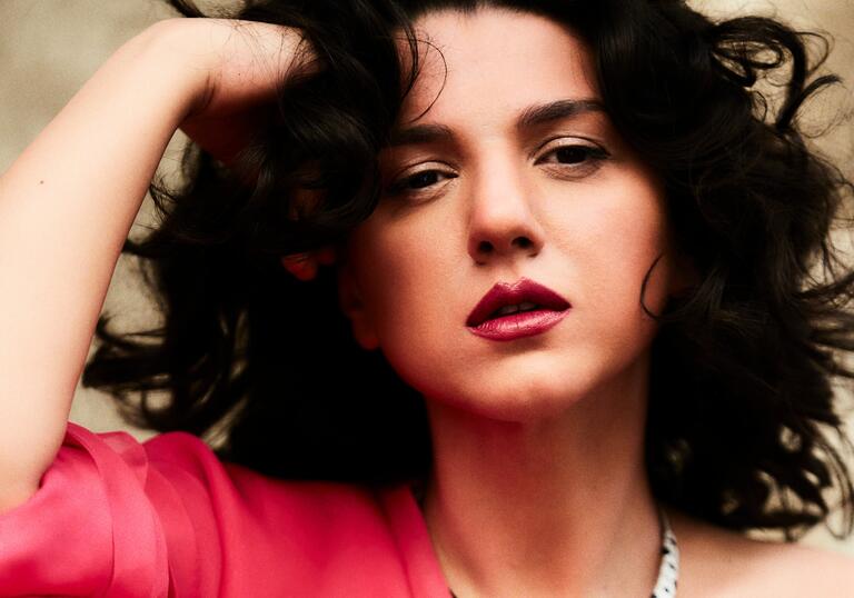 Khatia Buniatishvili wearing a coral pink dress, resting her head on her hand