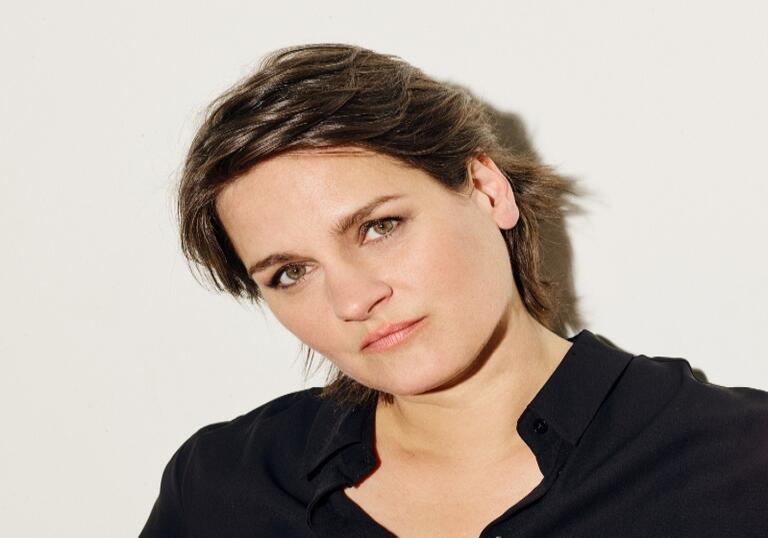 Madeline Peyroux, wearing black, looking into the camera