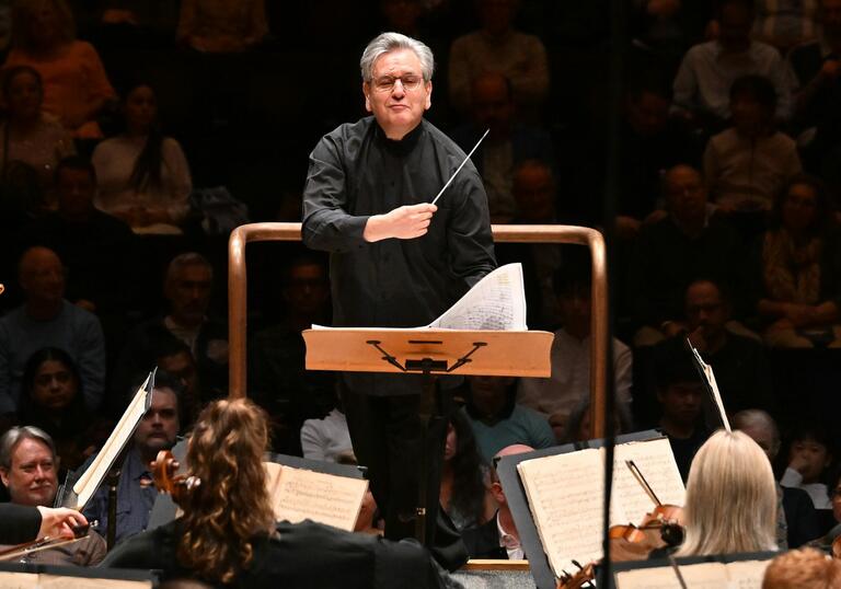 Sir Antonio Pappano conducting, smiling and facing the musicians of the LSO.